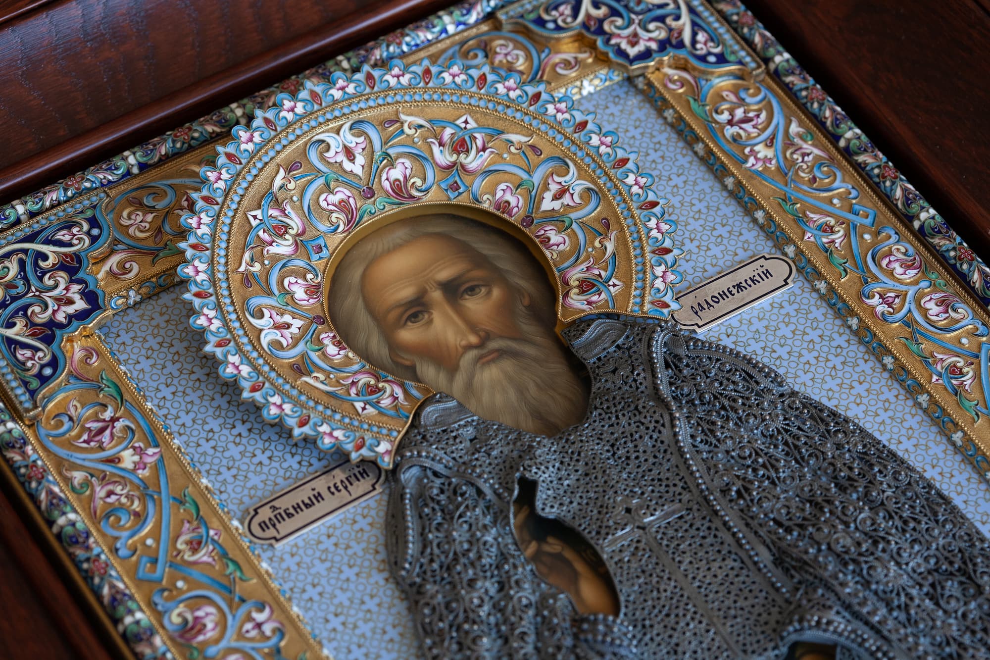 Рукописная икона Сергий Радонежский в серебряном окладе с эмалью и филигранью по цене 2500000 руб. Фото 2. Детальный фрагмент иконы Рукописная икона Сергий Радонежский в серебряном окладе с эмалью и филигранью по цене 2500000 руб. Фото 2. Детальная фотография лика Сергия Радонежского - темперная живопись, серебряный венец из скани и перегородчатой расписной эмали